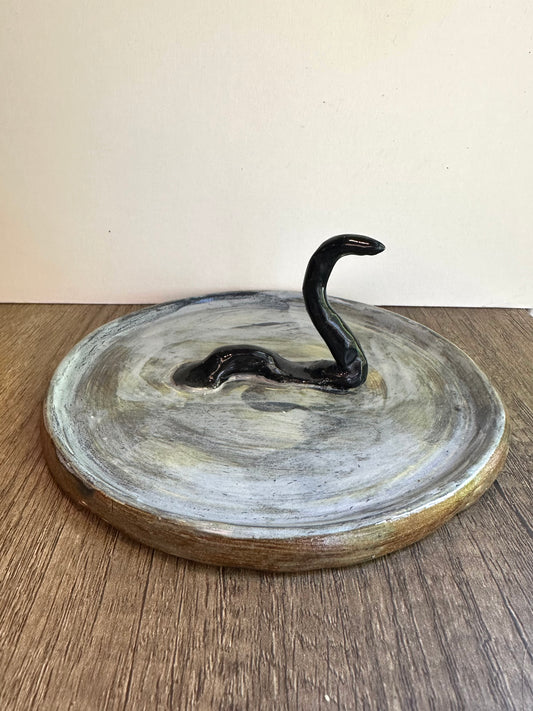 Loch Ness monster-inspired ring stand; black serpent in a pool of glossy, murky blue.