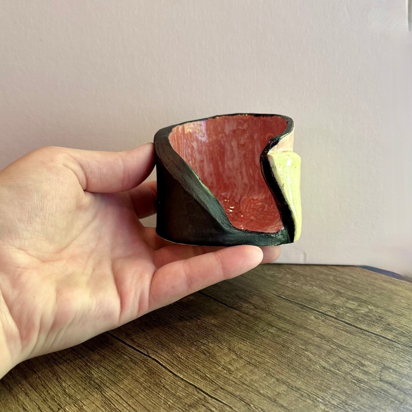 A hand holding the multi-colored votive for in-person scale reference.