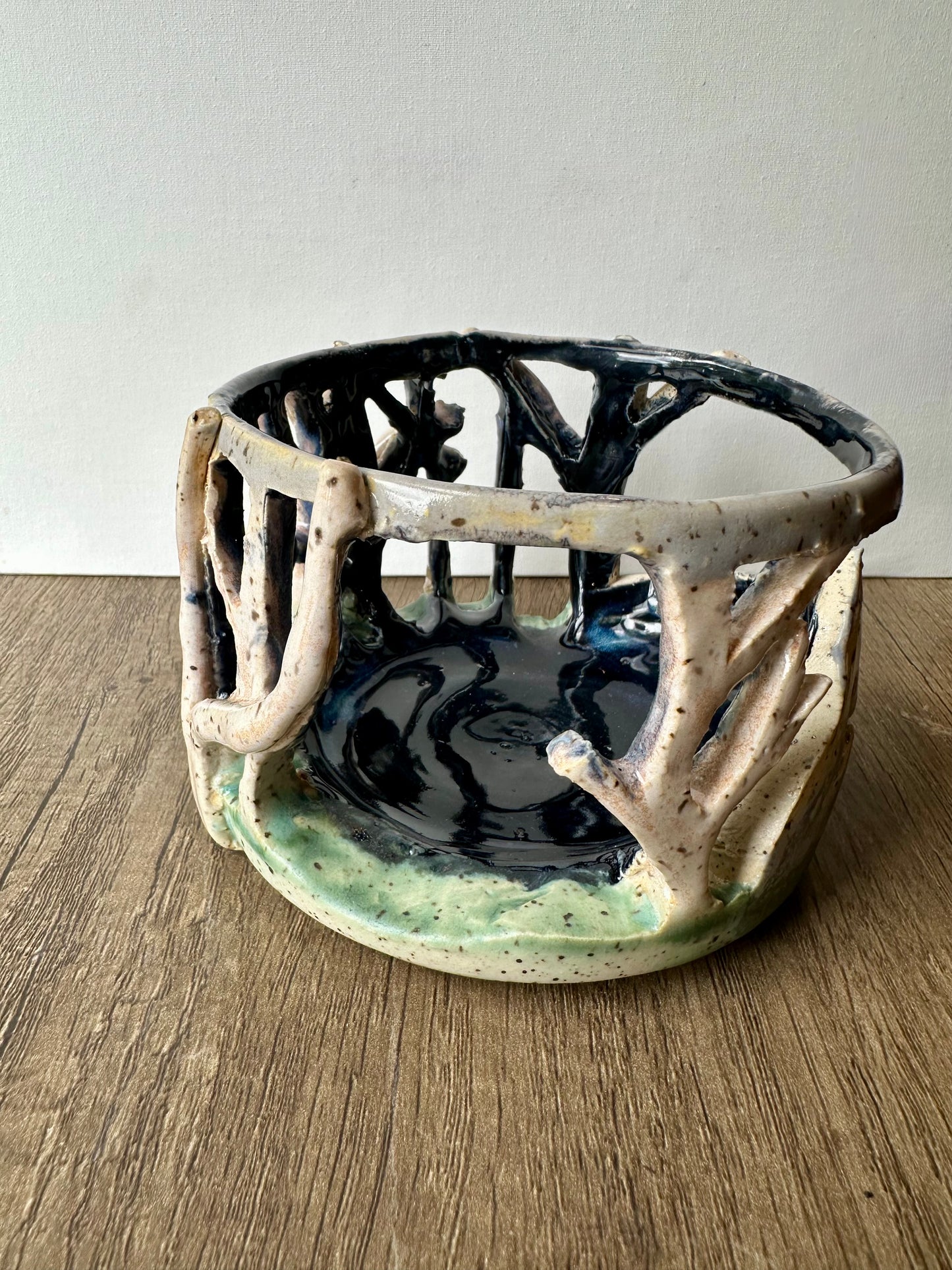 Round ceramic candle surround with mountain and birch trees cut out.