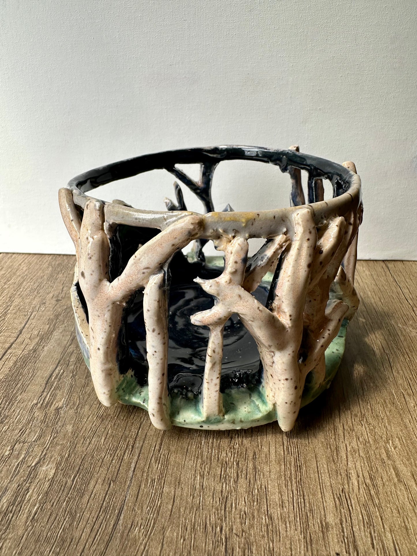 Round ceramic candle surround with mountain and birch trees cut out.