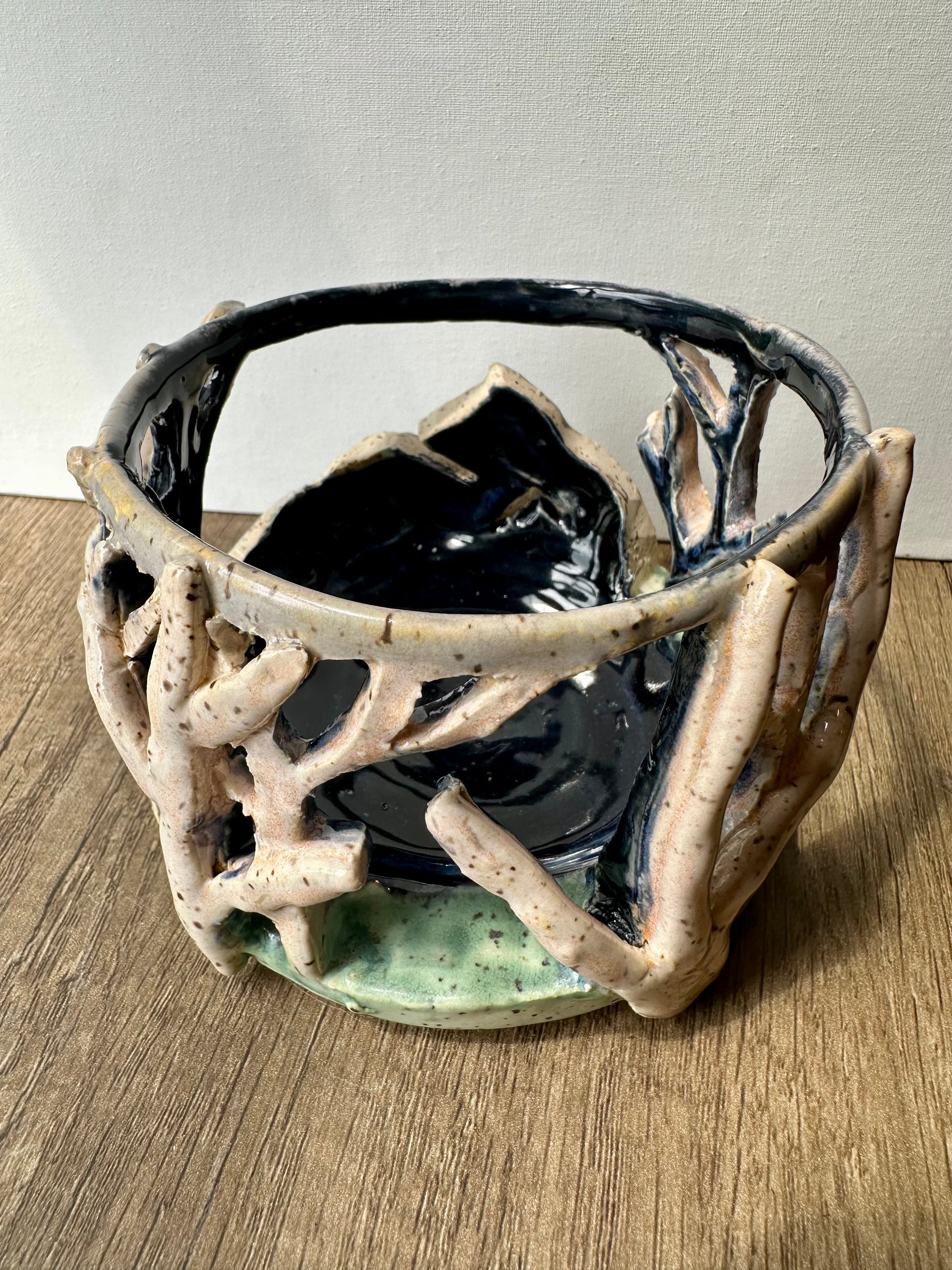 Round ceramic candle surround with mountain and birch trees cut out.