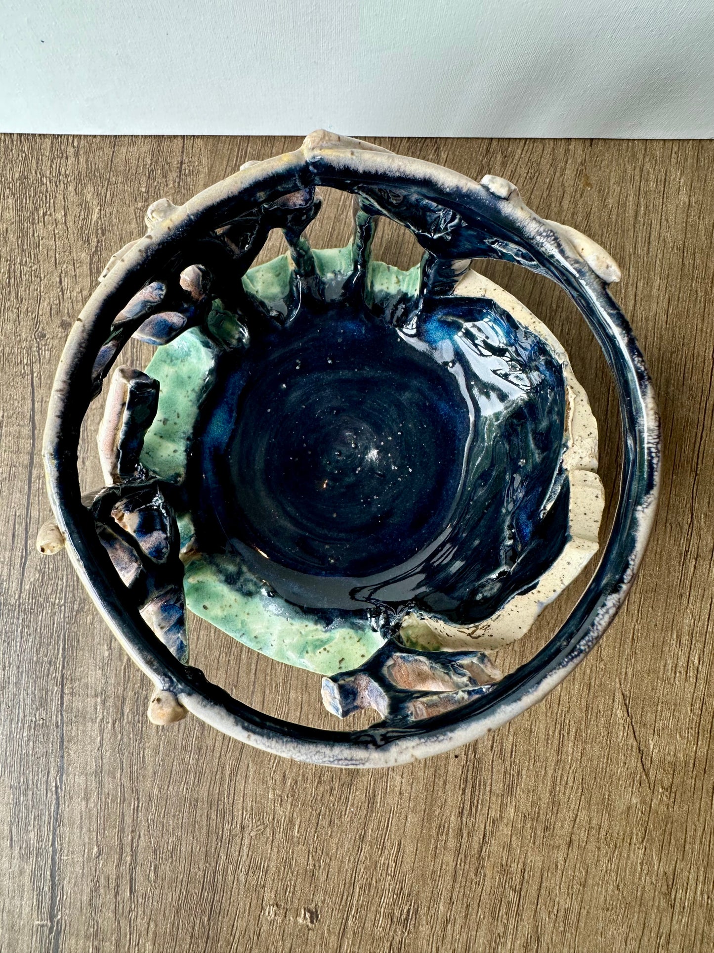 Overhead shot of the interior of round ceramic candle surround with mountain and birch trees cut out. Interior is inky blue.