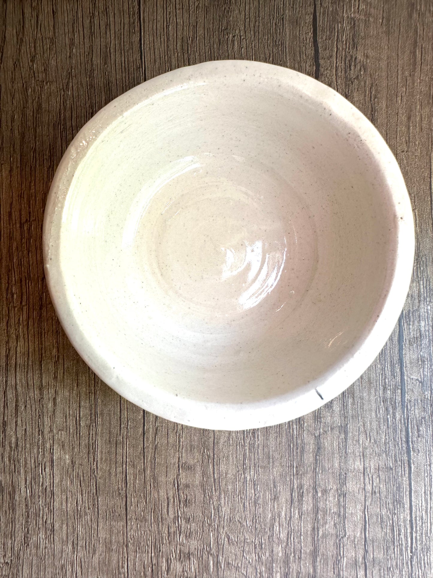 Interior of the body of the lidded trinket dish. Off-white, lightly speckled bowl shape with flat base.