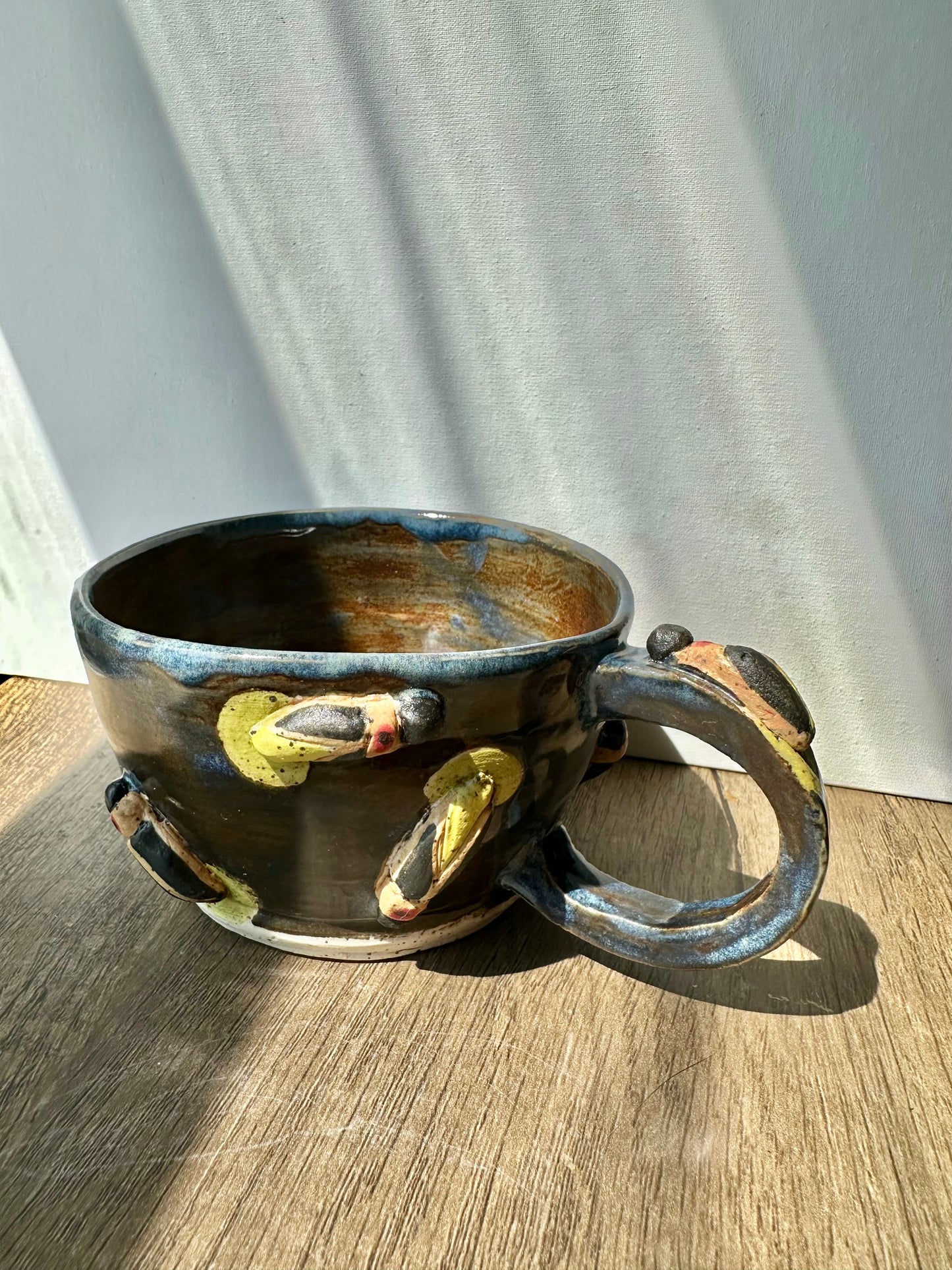 Bronze-colored mug with streaks of inky blue and sculpted fireflies.
