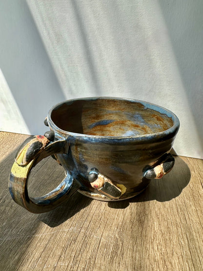 Bronze-colored mug with streaks of inky blue and sculpted fireflies.