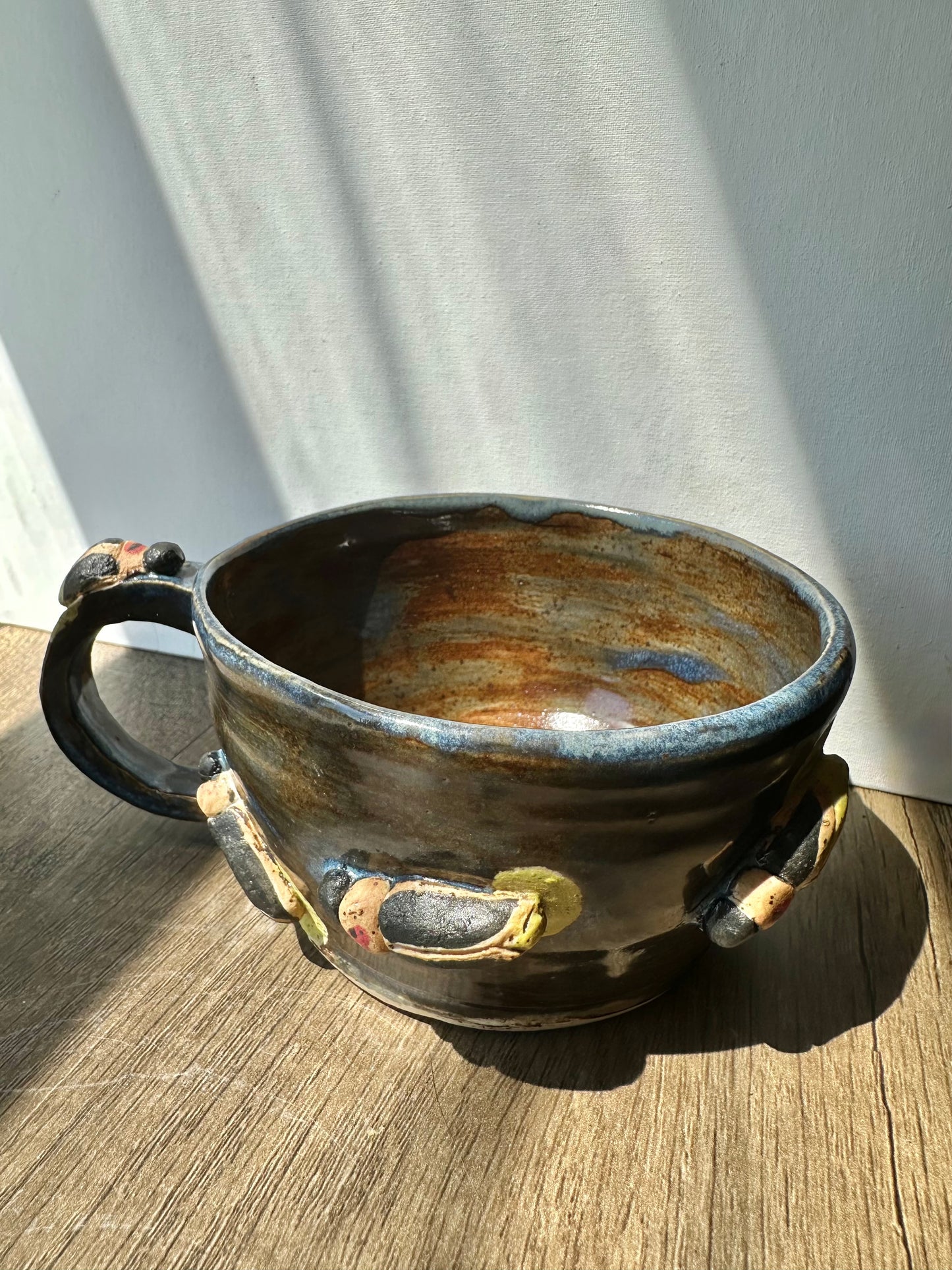 Bronze-colored mug with streaks of inky blue and sculpted fireflies.
