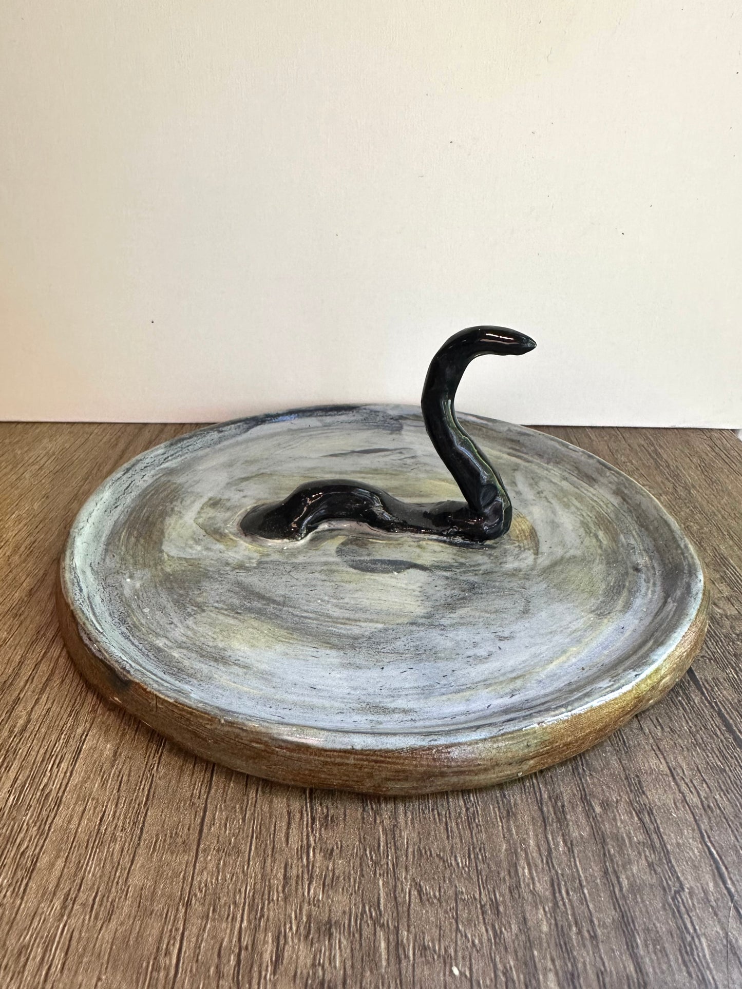 Loch Ness monster-inspired ring stand; black serpent in a pool of glossy, murky blue.