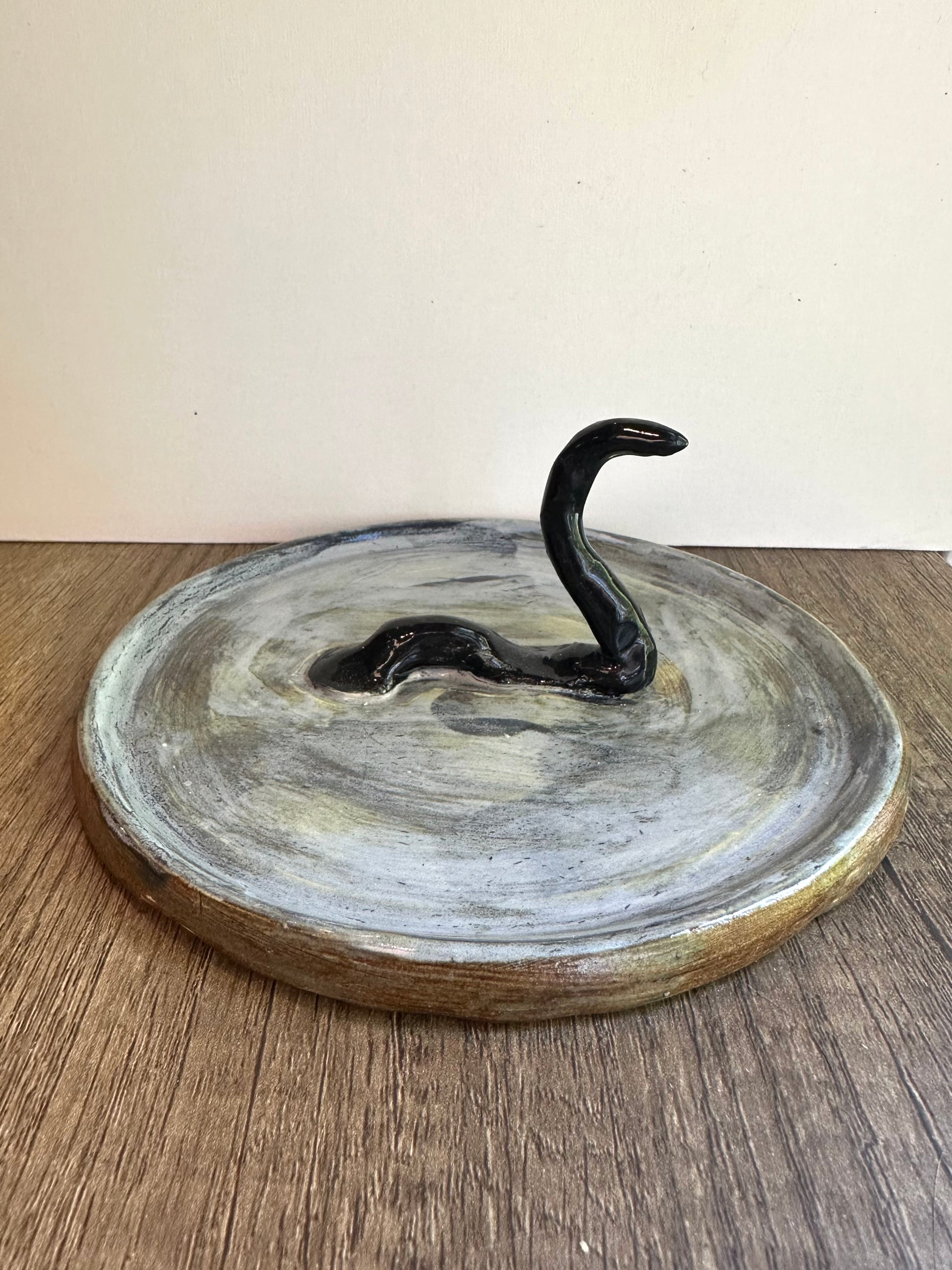 Loch Ness monster-inspired ring stand; black serpent in a pool of glossy, murky blue.