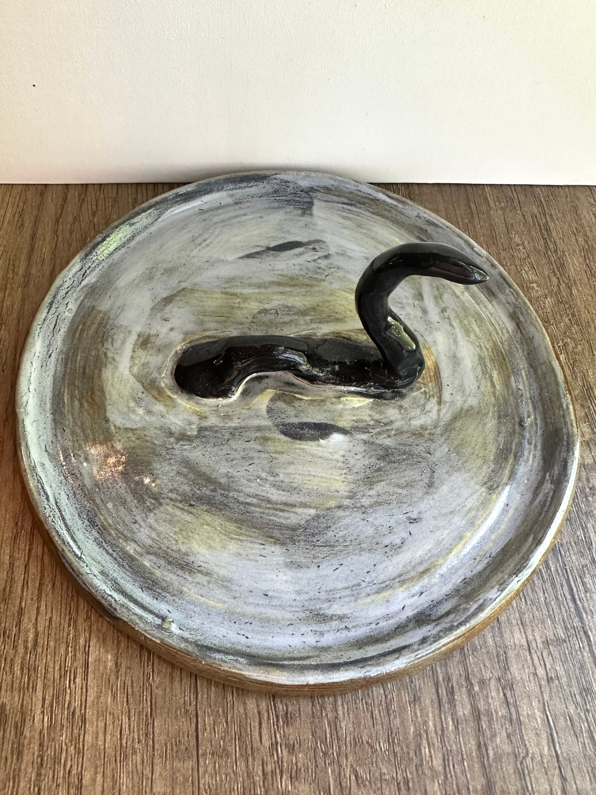 Loch Ness monster-inspired ring stand; black serpent in a pool of glossy, murky blue.