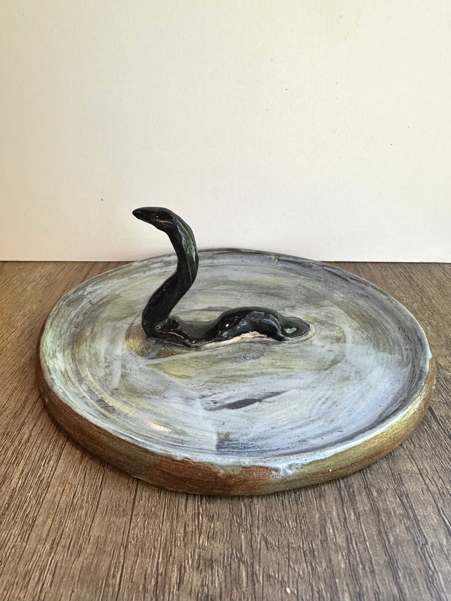Loch Ness monster-inspired ring stand; black serpent in a pool of glossy, murky blue.