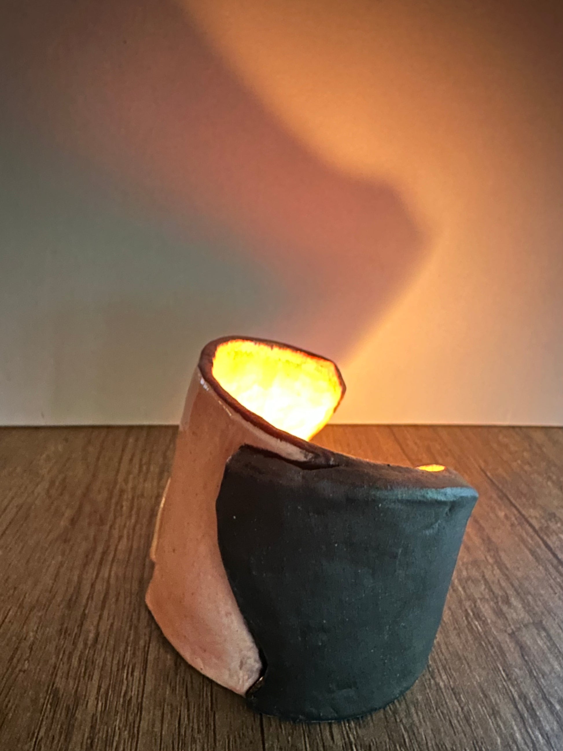 Ceramic multi-colored candle holder illuminated by a lit tea light.