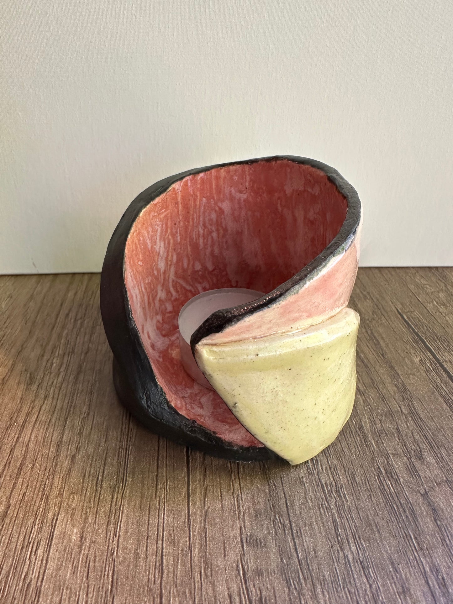 Ceramic multi-colored candle holder in neutral daylight with unlit tea light.