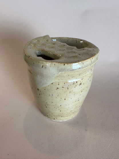 A beige speckled travel mug with half lid carved to look like a Dutch waffle cookie.